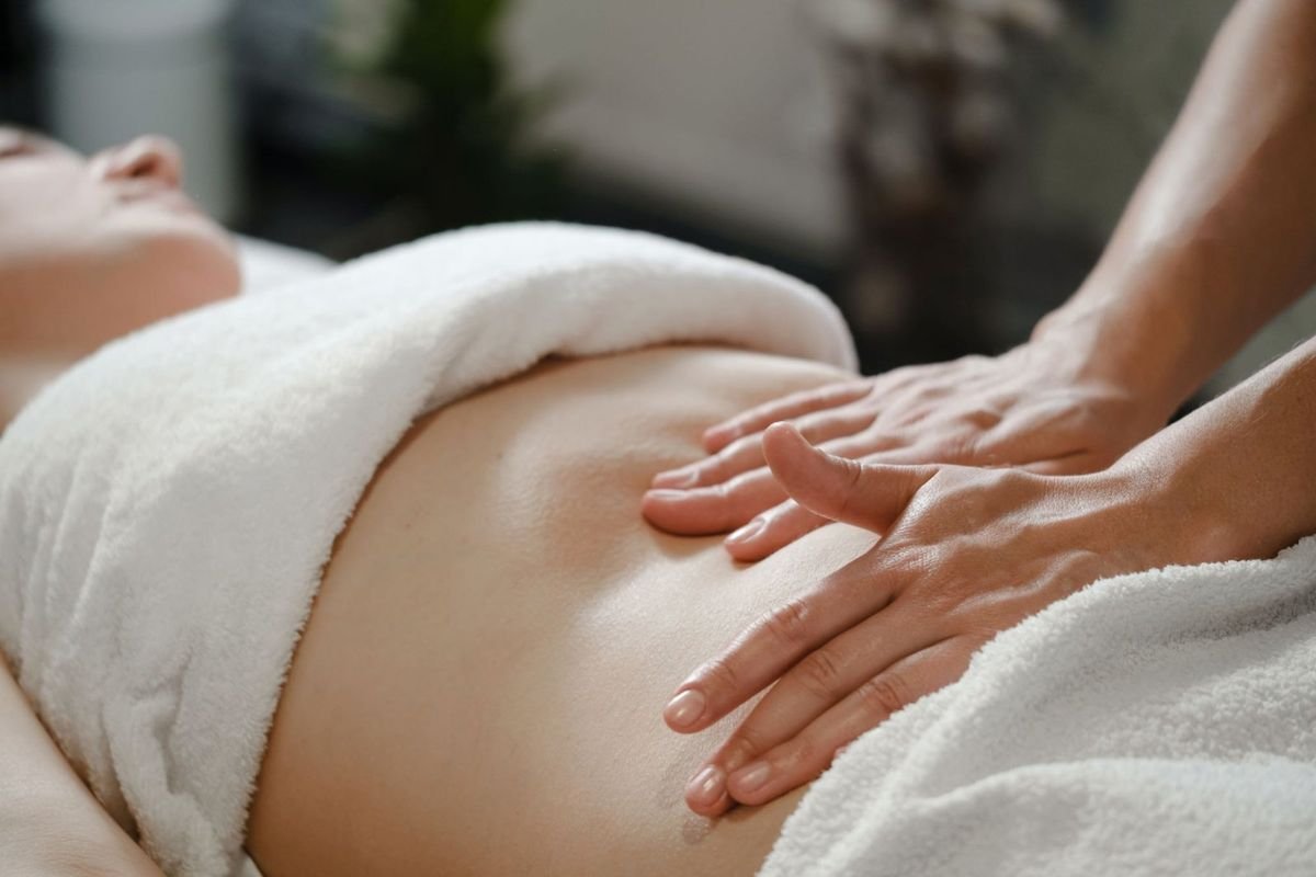 Mãos de terapeuta realizando drenagem linfática no abdômen
